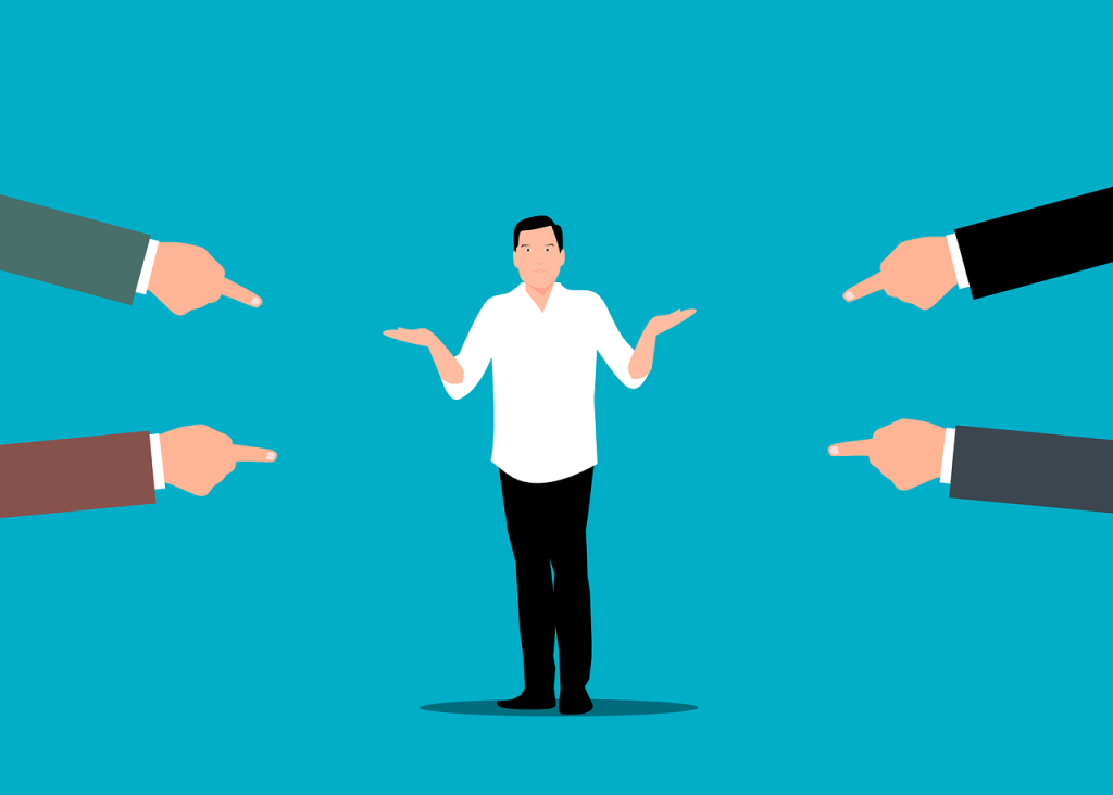 An illustration of hands pointing at a man like they are accusing him of being at fault. The man holds his hands up in a "i don't know" motion.