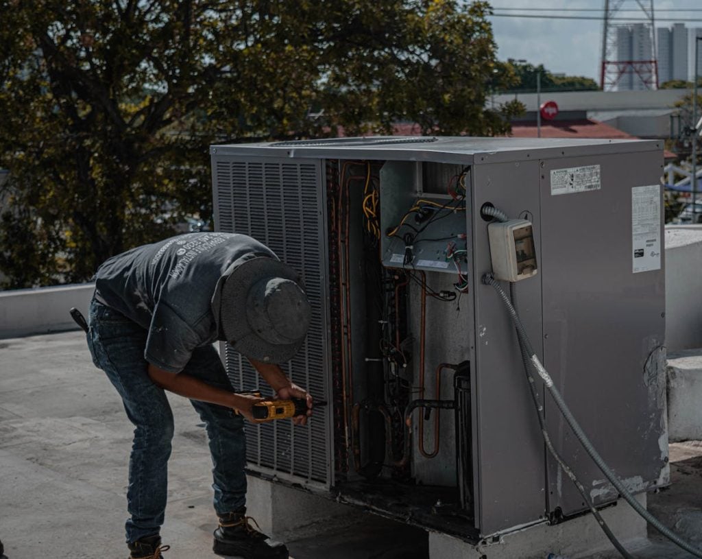 Photograph of a man unscrewing the cover to an HVAC unit
