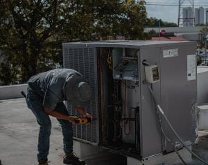 Photograph of a man unscrewing the cover to an HVAC unit