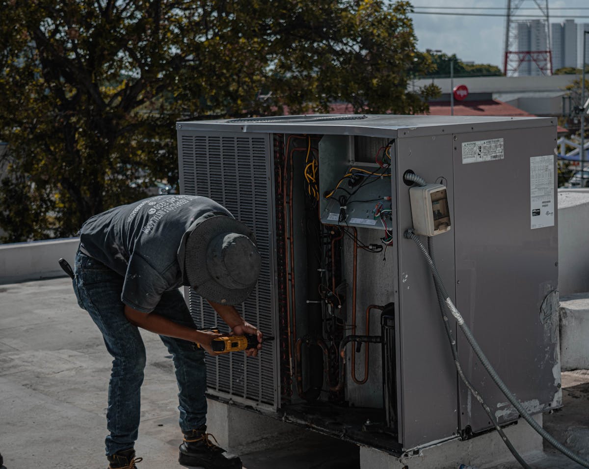 Photograph of a man unscrewing the cover to an HVAC unit