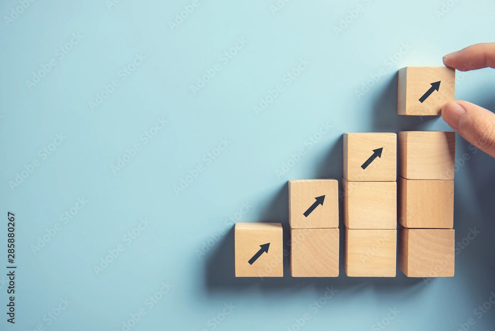 Hand stacking wooden blocks with upward arrows