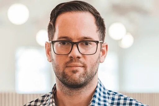 Man with glasses and trimmed beard indoors