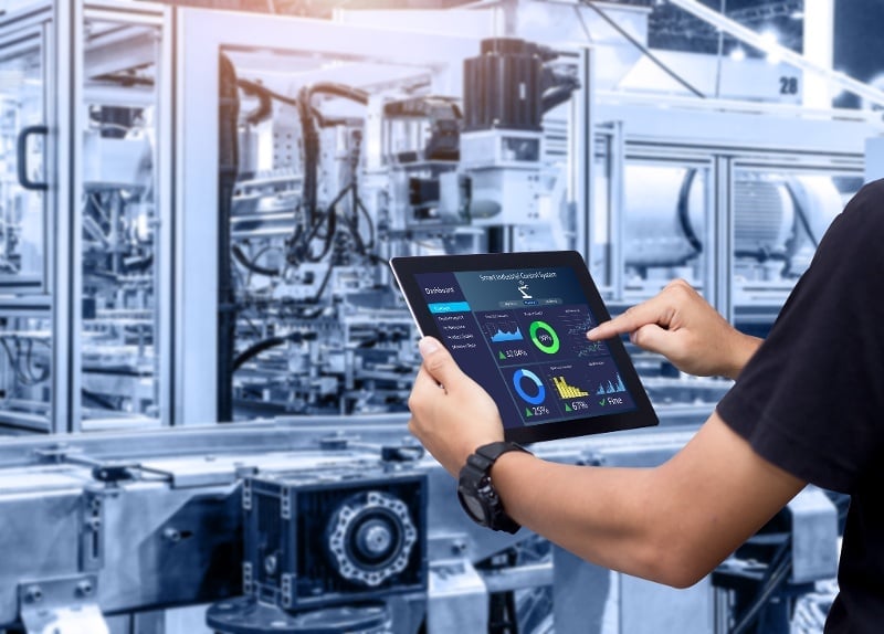 A man with an ipad controls large industrial equipment