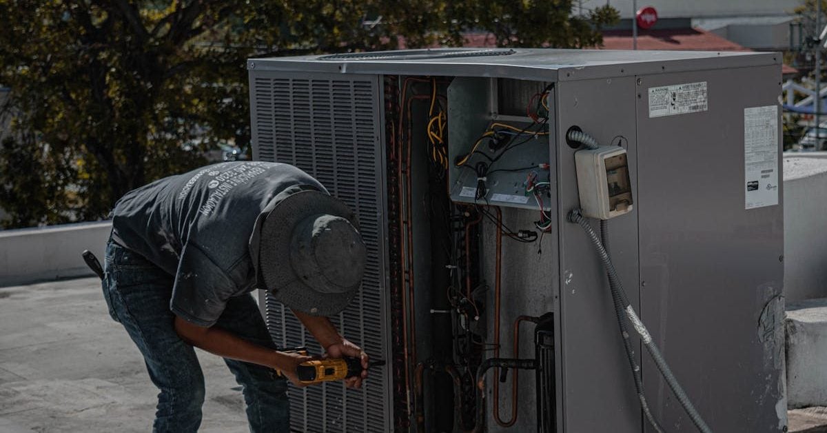 Photograph of a man unscrewing the cover to an HVAC unit