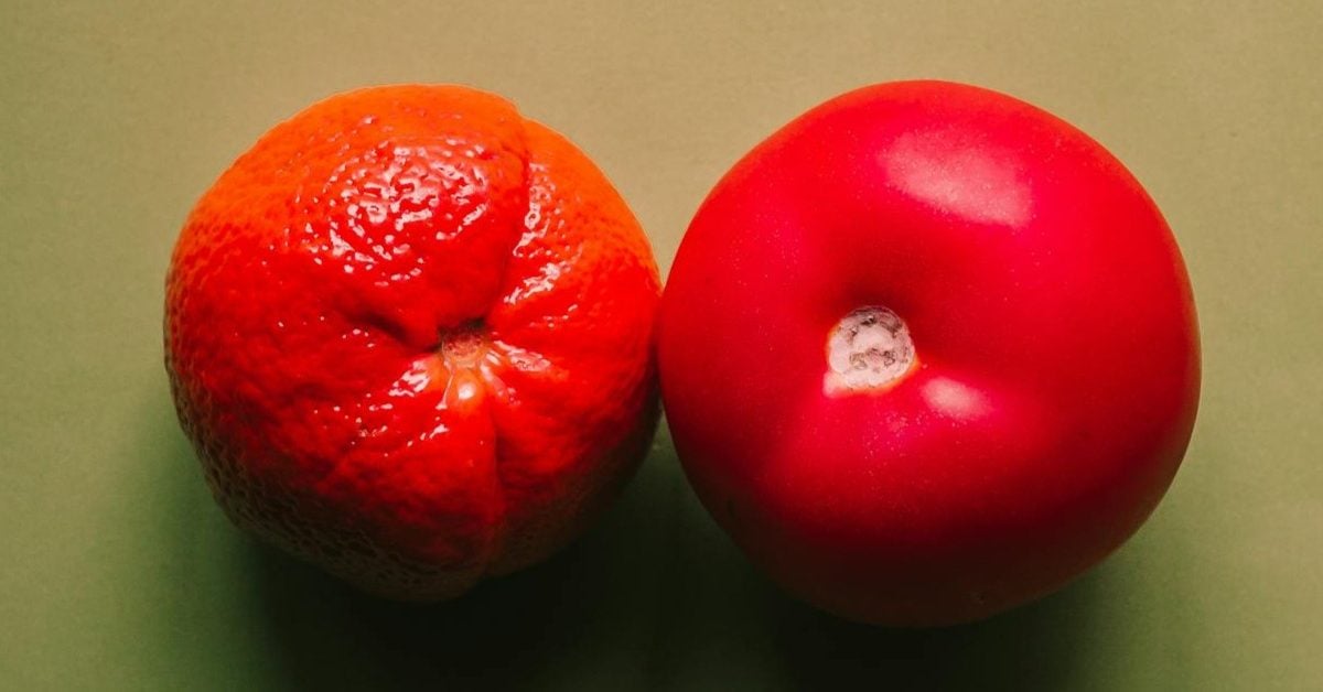 A photo of an apple and an orange side by side on a green background